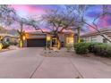 Attractive home exterior featuring a well-manicured desert landscape, mature trees and a dark garage door at 16013 N 111Th Pl, Scottsdale, AZ 85255