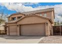 Close-up of two-story home with terracotta tile roof and attached three-car garage at 3239 E San Manuel Rd, San Tan Valley, AZ 85143