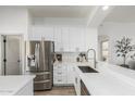 Elegant white kitchen featuring stainless steel refrigerator and breakfast bar area with sink at 3872 S Seton Ave, Gilbert, AZ 85297