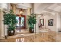 Grand foyer entrance with marble floors, decorative columns, elegant light fixture, and a glimpse of the dining room at 40635 N 109Th Pl, Scottsdale, AZ 85262