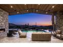 Inviting outdoor living space at sunset, with a stone fireplace and view of the pool and desert landscape at 41248 N 96Th St, Scottsdale, AZ 85262