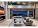 Elegant living room featuring stone accents, a fireplace, and seamless access to outdoor pool at 9643 E Cintarosa Pass, Scottsdale, AZ 85262