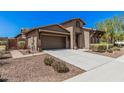 A single-Gathering home showcases desert landscaping, a front door with security gate, and a two car garage at 13641 W Jesse Red Dr, Peoria, AZ 85383