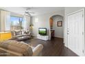 Comfortable living room with wood floors, large window with white curtains, and arched doorway to office space at 29606 N Tatum Blvd # 128, Cave Creek, AZ 85331
