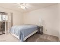 Cozy bedroom has a ceiling fan and a sliding glass door for ample natural light at 8155 E Roosevelt St # 204, Scottsdale, AZ 85257
