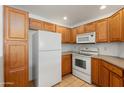 Condo kitchen featuring wood cabinets, white appliances, and tile floors, combining efficiency and a clean design at 14000 N 94Th St # 3094, Scottsdale, AZ 85260