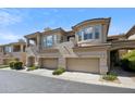 Inviting view of the townhome's facade, featuring a two-car garage, balcony, and desert landscaping in a gated community at 16420 N Thompson Peak Pkwy # 2091, Scottsdale, AZ 85260