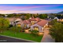 Expansive aerial view of a luxurious home with a terracotta roof, showcasing its three-car garage and lush green surroundings at 17755 E Colt Dr, Queen Creek, AZ 85142