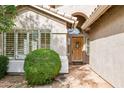 Close-up of the home's entryway with a wooden front door, well-manicured landscaping, and a stucco exterior at 17828 N 50Th St, Scottsdale, AZ 85254