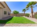 Picture-perfect backyard with a green lawn, desert landscaping, beautiful palm trees, and a brick patio, ideal for outdoor living at 37180 W Mondragone Ln, Maricopa, AZ 85138