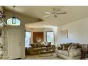 Bright living room featuring a vaulted ceiling, ceiling fan, large windows, and neutral colored couches at 4643 E Cherry Hills Dr, Chandler, AZ 85249