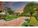 Expansive backyard boasts lush green lawn, vibrant flowerbeds, mature trees, and a charming wooden pergola for outdoor relaxation at 12 E Oakwood Hills Dr, Chandler, AZ 85248