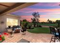 Inviting covered patio with comfortable seating, a fire pit, and picturesque golf course views at 23108 N Pedregosa Dr, Sun City West, AZ 85375