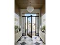 Elegant foyer with a black and white checkered floor, a modern chandelier, and a view of the front yard at 6147 E Desert Cove Ave, Scottsdale, AZ 85254
