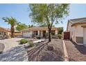 Single-story home showcases a tile roof, desert landscaping, and a covered front porch with a view of palm trees at 6659 W Oraibi Dr, Glendale, AZ 85308