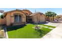 Inviting front yard with artificial grass, desert landscaping and walkway stones at 12749 W Sheridan St, Avondale, AZ 85392