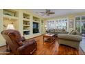 Comfortable living room featuring hardwood floors, custom built-ins, and large windows with plantation shutters at 19212 N Tallowood Way, Surprise, AZ 85387