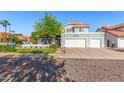 Inviting home showcasing lush landscaping, a mature shade tree, and a convenient three-car garage at 2218 E Mallard Ct, Gilbert, AZ 85234
