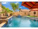 Beautiful backyard pool with waterfalls, lush landscaping, and lounge chairs under a colorful umbrella at 2318 W Hedgehog Pl, Phoenix, AZ 85085