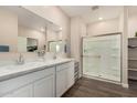 Well-lit bathroom featuring dual sinks, wood-look flooring, and a glass-enclosed walk-in shower at 2475 W Spaulding Ave, Apache Junction, AZ 85120
