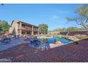 Expansive backyard featuring a pool, outdoor seating, lawn, mature trees, and a two-story house at 25767 N 67Th Dr, Peoria, AZ 85383