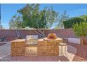 Backyard featuring an outdoor kitchen with stone counter, grill, pizza oven, and bar seating at 25767 N 67Th Dr, Peoria, AZ 85383