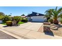 View of the home's exterior with desert landscaping, green grass, and a driveway leading to a two-car garage at 2717 E Aster Dr, Phoenix, AZ 85032