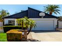 View of the garage with a basketball hoop and tropical landscaping surrounding the driveway and facade at 2717 E Aster Dr, Phoenix, AZ 85032