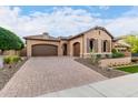 Elegant home with a three-car garage, brick driveway, desert landscaping, and neutral-toned exterior paint at 28834 N 68Th Ave, Peoria, AZ 85383