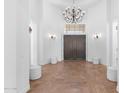 Grand foyer featuring high ceilings, a wrought iron chandelier, stone floors, and a beautiful arched entryway at 30311 N 52Nd Pl, Cave Creek, AZ 85331