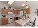 Well-lit kitchen features wooden cabinets, tile floors, modern appliances, breakfast bar, and a bright window at 4450 E Amberwood Dr, Phoenix, AZ 85048