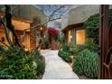 Stunning desert home entrance featuring lush plants, stone accents, and a warm, inviting ambiance at 9722 E Mark Ln, Scottsdale, AZ 85262