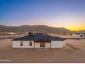 The back exterior features a minimalist covered patio and picture windows with sunset desert mountain views at 16567 N Slate Ln, Maricopa, AZ 85139