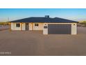 Charming single-story home featuring a gray garage door, minimalist landscaping, and stylish exterior lighting at 16567 N Slate Ln, Maricopa, AZ 85139