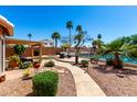 Serene backyard boasts a winding stone path, lush landscaping, and a tranquil water view with mature palm trees at 1741 S Clearview Ave # 70, Mesa, AZ 85209