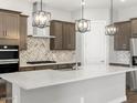Kitchen featuring stainless appliances, quartz countertops, tile backsplash, and pendant lighting at 17621 W Pierson St, Goodyear, AZ 85395