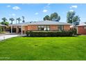 Charming single-story brick home featuring a well-manicured lawn, carport, and trimmed hedge landscaping at 1939 E Solano Dr, Phoenix, AZ 85016
