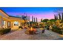 Inviting backyard features a fire pit, spiral staircase, lush landscaping, and well-lit patio area for outdoor enjoyment at 2174 E Avenida Del Valle Ct, Gilbert, AZ 85298