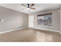 Well-lit living room with tile flooring, ceiling fan, and a large window with natural light at 8014 W Mescal St, Peoria, AZ 85345
