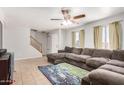 Bright living room with large sectional sofa, ceiling fan, stairs, tile flooring, and natural light at 8226 N 32Nd Dr, Phoenix, AZ 85051