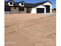 A white house with black trim and a black roof, showing a large garage and a spacious yard at 11142 E Copper Dust Trl, Florence, AZ 85132