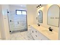 Bright bathroom featuring a double vanity, sleek black fixtures, and a glass-enclosed shower with marble tiling at 11142 E Copper Dust Trl, Florence, AZ 85132