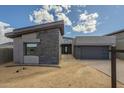 Striking exterior of a modern home featuring stone accents, a gray garage door, and a neatly paved driveway at 12328 E Black Rock Rd, Scottsdale, AZ 85255
