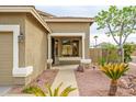Inviting covered front porch with neutral columns, desert landscaping, and mature palm trees enhancing curb appeal at 15123 W Custer Ln, Surprise, AZ 85379