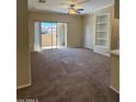 Spacious living room featuring modern ceiling fan, built-in shelving and sliding glass door to patio at 16013 S Desert Foothills Pkwy # 1050, Phoenix, AZ 85048