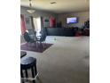 Large living room with black sofa, carpeted floors and big-screen television with a view to the patio at 19427 N Toya St, Maricopa, AZ 85138
