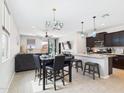 Open concept kitchen and dining area features pendant lights, black cabinets, and tile floors at 235 S San Gregorio Ln, Casa Grande, AZ 85194