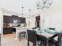 Open concept kitchen and dining area features pendant lights, black cabinets, and tile floors at 235 S San Gregorio Ln, Casa Grande, AZ 85194