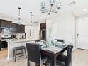 Open concept kitchen and dining area features pendant lights, black cabinets, and tile floors at 235 S San Gregorio Ln, Casa Grande, AZ 85194