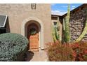 Inviting front entrance with a decorative wooden door, desert plants, and a stone-accented facade at 27280 N Makena Pl, Peoria, AZ 85383